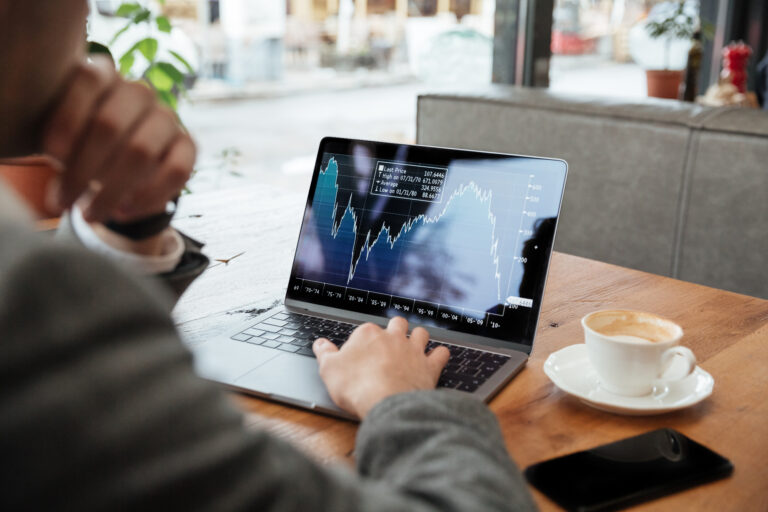 Cropped image of business man sitting by the table in cafe and analyzing indicators